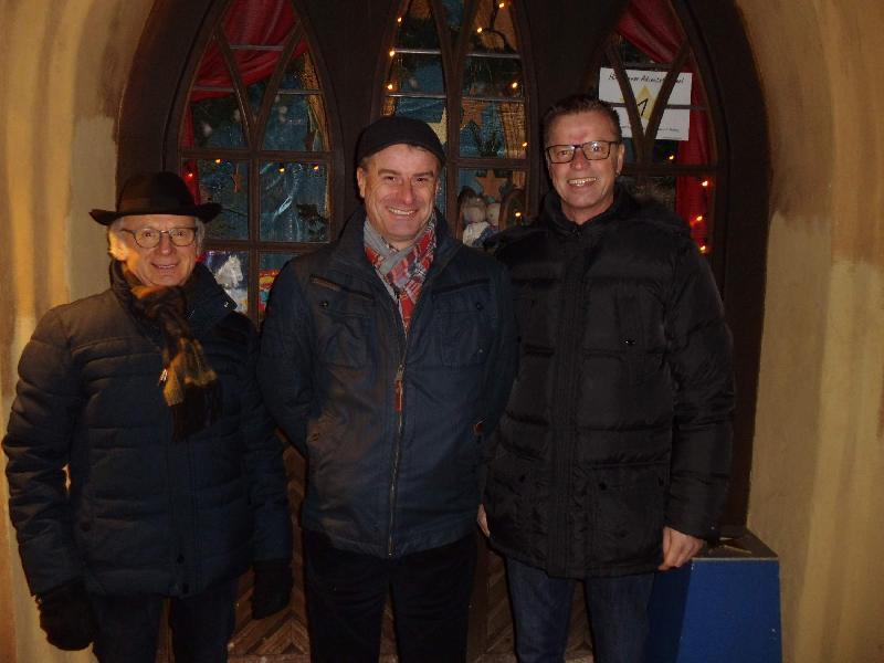 Bürgermeister Hermann Falk (r.) öffnete am Sonntag das erste Türchen des 19. Lebendigen Adventskalenders. Er dankte allen, die zum Gelingen der Veranstaltungsreihe beitragen. Dies tat auch der Gewerbeverbandsvorsitzende Alfred Härtl (l.). Er wies auf die Spendenbox hin, deren Inhalt für den Hospizverein Amberg e.V. bestimmt ist. Bildmitte: Gaston Lottner, der stellvertretende Vorsitzende des Heimat- und Trachtenvereins, dessen Mitglieder allabendlich die kulinarische Versorgung der Besucher übernehmen. - Foto von Werner Schulz
