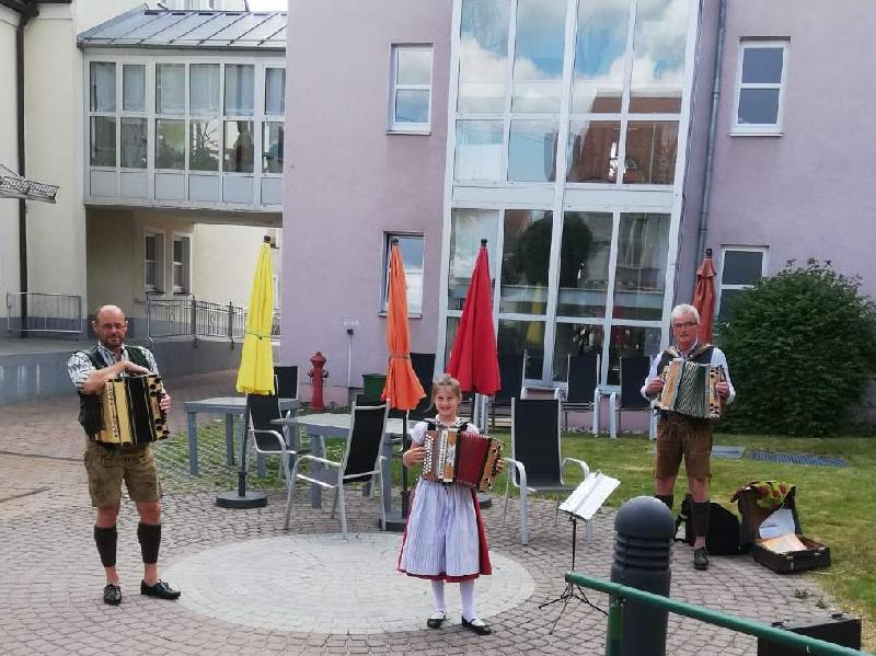 Zünftig bayerisch und beschwingt spielte auf Initiative von Hanna Ries (Mitte) das Trachtler-Musikantentrio am Muttertag im Innenhof des BRK-Seniorenwohn- und Pflegeheims auf und bereitete damit den Senior*innen eine freudige Überraschung und willkommene Abwechslung vom Corona-Alltag. Mit im Bild: Uwe Herrmann (l.) und Franz Dolles (r.). - Foto von Werner Schulz