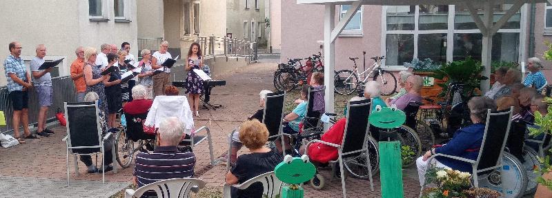 Mit seiner Sommerserenade bereitete der Gemischte Chor unter Leitung von Jana Müller (stehend vorne r.) den Bewohnern des BRK Seniorenwohn- und Pflegeheims St. Barbara und den zahlreichen Gästen einen gleichermaßen stimmungsvollen wie kurzweiligen Abend. - Foto von Werner Schulz