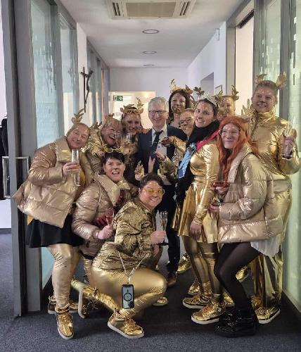 Vom Monte-Brunnen mit den beiden goldenen Hirschen inspiriert , kam Narrhalla-Präsidentin Regina Merkl vor vier Jahren auf die Idee, am Unsinnigen Donnerstag mit einigen Hofdamen die Innenstadt unsicher zu machen – verkleidet als „goldene Hirschis“. Bei der Premiere war es ein „Hirschi-Septett“, das durch Hirschau streifte. Dieses Mal zog ein elf-köpfiges Rudel von Geschäft zu Geschäft, von Lokal zu Lokal. Wie sich „Hirschis“ vermehren, ist noch nicht erforscht – sind doch allesamt weiblichen Geschlechts. In ihren goldenen Kostümen erschienen sie beim Dorner Boder, im Friseurladen Rossi und im Schmuckgeschäft Huber genauso wie im Gasthof Weich, im „Goldenen Hirsch“ und im Pizza-Häuschen, ja sogar in der Zahnarztpraxis Dr. Schönberger. Die Geschäftsleute konnten den Gästen ein Tänzchen nicht verwehren, sangen mit ihnen alt bekannte Faschingslieder und zogen per Polonaise durch die Lokale bzw. Geschäfte. Leicht frustriert waren die „Hirschis“ trotzdem, nur im Schmuckgeschäft Huber war ein Mann mit Krawatte anzutreffen. Was ist ein Unsinniger Donnerstag ohne abgeschnittene Krawatten? Im Rathaus fand man mit Bürgermeister Hermann Falk endlich ein Opfer. Kaum hatte das Hirschi-Rudel sein Amtszimmer betreten, schritt Prinzessin Jessica I. zur Tat. Sie zückte schnitt dem Rathaus-Chef das Symbol männlicher Macht kurzerhand ab. In der Sparkasse musste die Krawatte von Filialleiter Dominik Merkel dran glauben. Dagegen half auch der 100-Euro-Scheck nicht, den er überreichte. In der Raiffeisenbank fand man mit Vorstand Klaus Wild ein weiteres Schlipsopfer. Auf ihrem anschließenden Streifzug zeigten sich die „Hirschis“ spendabel. Ob Erwachsene oder Kinder – sie wurden großzügig mit Bonbons versorgt. Regina Merkls Fazit beim letzten Stopp in der Pizzeria Pino: „Es woa einfach wieder superschöi!“ - Foto von Werner Schulz